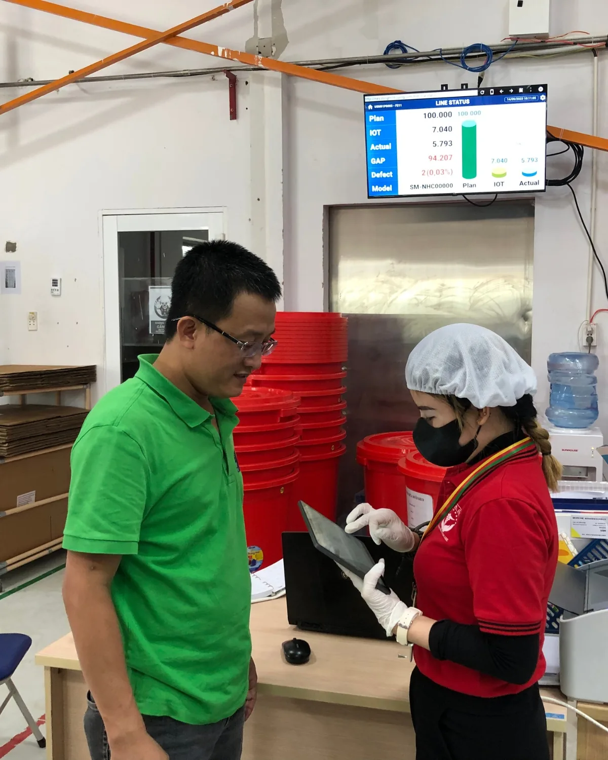 Hướng dẫn công nhân ghi nhận sản xuất trên tablet, màn hình trạng thái chuyền phía sau